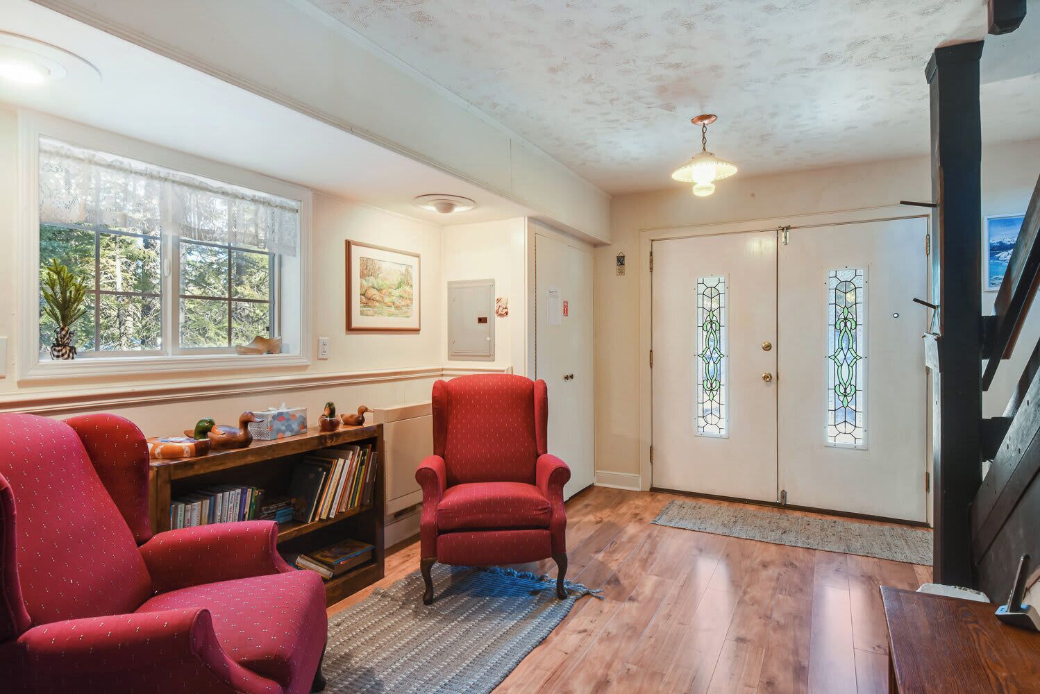 A living room with a fireplace, a bookshelf, and a red armchair.