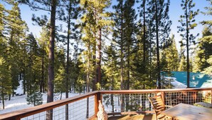 A wooden deck with a table and chairs, surrounded by tall pine trees and a snow-covered ground. - Woodside Hideout | Hop Away from Activities (Tahoma)