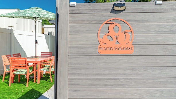 Une clôture en bois sur laquelle figure un logo et l’inscription « PEACHY PARADISE ».