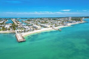 An aerial view of a coastal resort with a marina, beachfront, and dense residential buildings. - *NEW* Finer Things-Beach/Pool (Key Colony Beach)