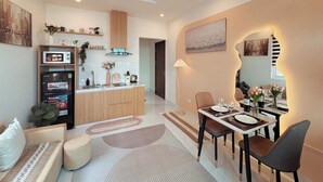 Une cuisine moderne dotée d’un îlot central, un coin repas avec une table dressée pour deux personnes, et un espace de vie comprenant un canapé et une table basse.