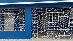 Un edificio con dos ventanas adornadas con complejas rejas de metal blanco.