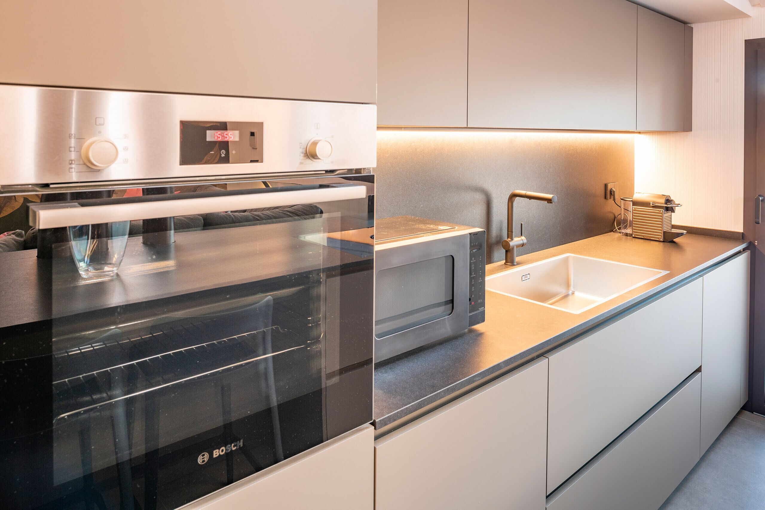Een moderne keuken met een Bosch oven, een magnetron, een spoelbak en een koffieapparaat.