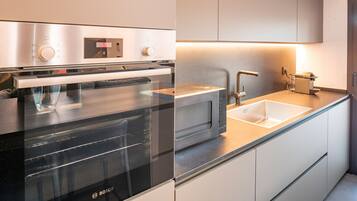 Een moderne keuken met een Bosch oven, een magnetron, een spoelbak en een koffieapparaat.