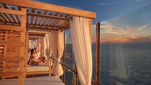 A couple relaxing on a wooden deck with a view of the ocean.