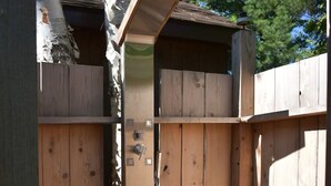 Eine Holzdielen-Terrasse mit integriertem Sitz und einem kleinen, umzäunten Bereich mit einer Holztür.