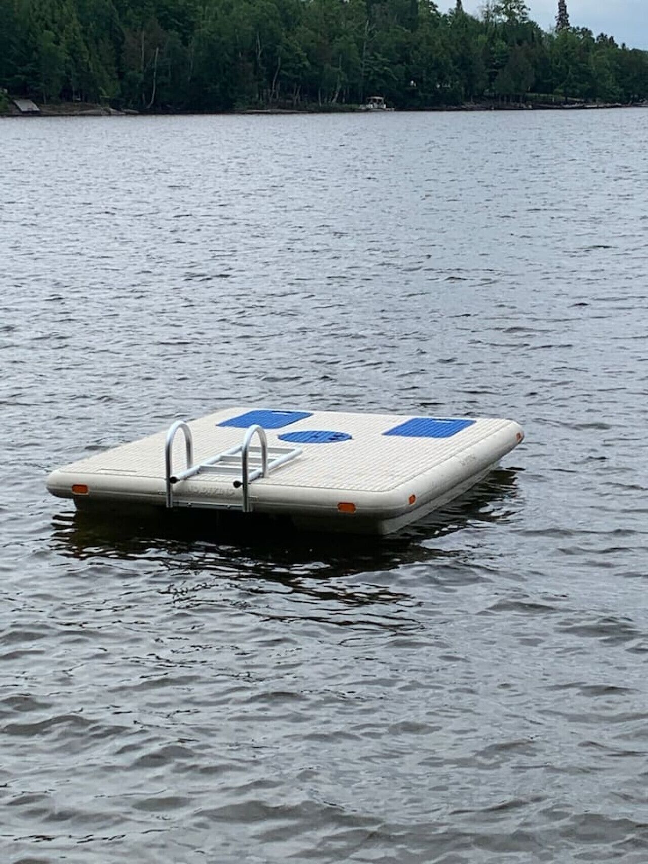 Una plataforma flotante con una escalera, rodeada de aguas tranquilas.