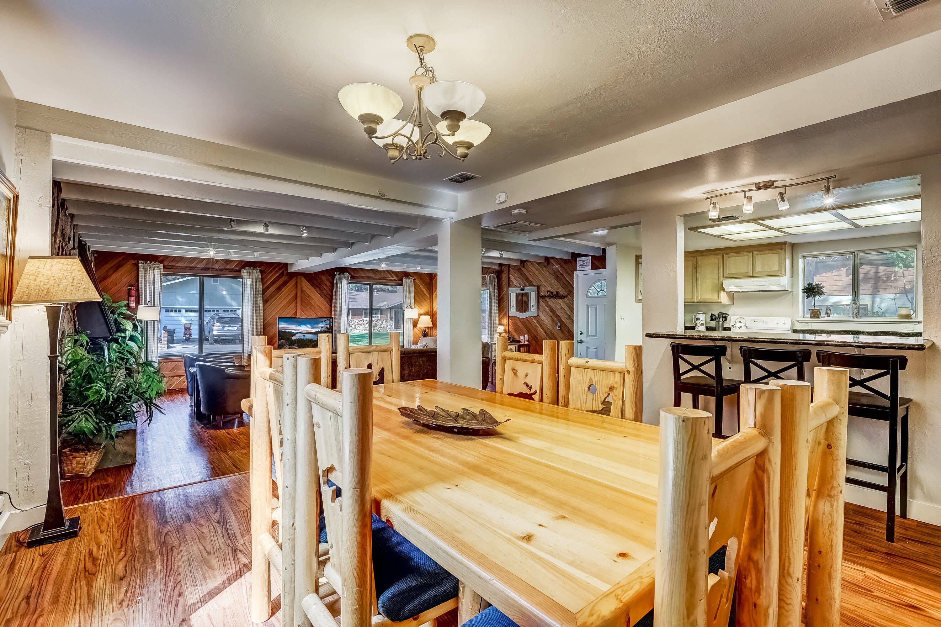 Un'ampia sala da pranzo con tavolo e sedie in legno, un lampadario e vista sull'esterno.