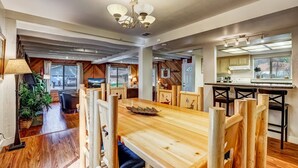 Un comedor amplio con una mesa y sillas de madera, un candelabro y vistas al exterior.