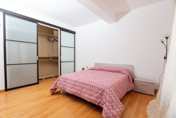 A bedroom with a bed, a wardrobe, and a nightstand. - LuminArt (Gibellina)