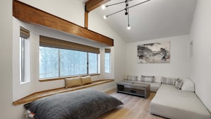 Un dormitorio tipo loft moderno con cama alta, asientos integrados tipo banco, un sofá y un cuadro abstracto grande.
