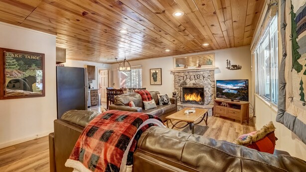 Una sala de estar acogedora con chimenea, sofás de cuero, televisor y un revestimiento de piedra alrededor de la chimenea.