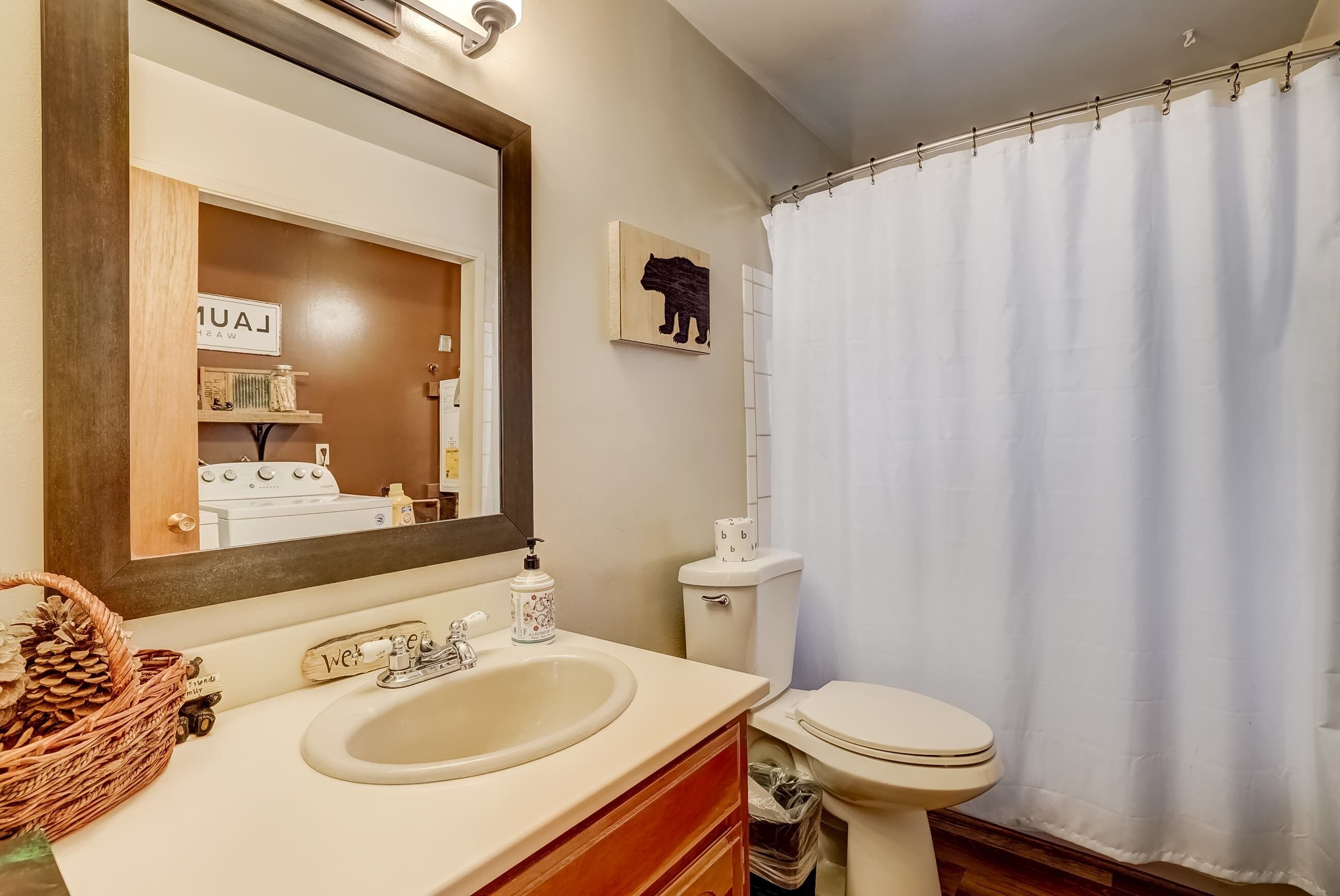 A bathroom with a sink, mirror, toilet, and shower curtain.