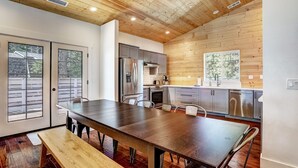 Una cocina moderna con techo de madera, electrodomésticos de acero inoxidable y una amplia mesa de comedor.