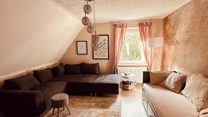Un acogedor dormitorio tipo loft con cama en el altillo, sofá cama y una pequeña mesa.