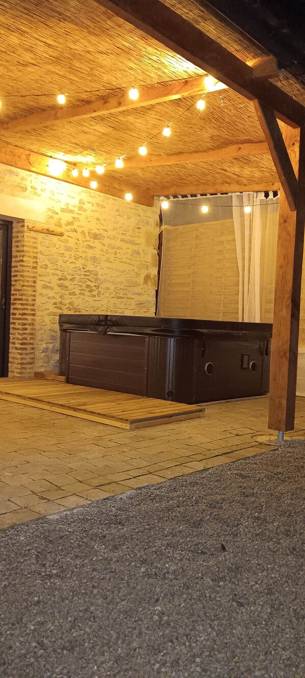 Una habitación rústica con una cama de madera, paredes de piedra y techo de paja.