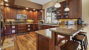 A spacious kitchen with wooden cabinets, a granite countertop, and a large island with bar stools.