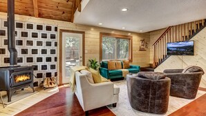 Una sala de estar acogedora con chimenea, paredes de madera y una escalera.