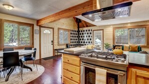 Una cocina con una isla central, armarios de madera, una estufa y un comedor con sillas y una mesa.
