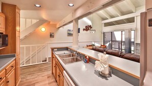 A kitchen with a large island, wooden cabinets, and a built-in microwave.