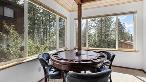 A round wooden table with four chairs in a room with large windows overlooking a forest. - Hall Court Manor - Hot tub, Pet Friendly, Pool Table! (Stateline)