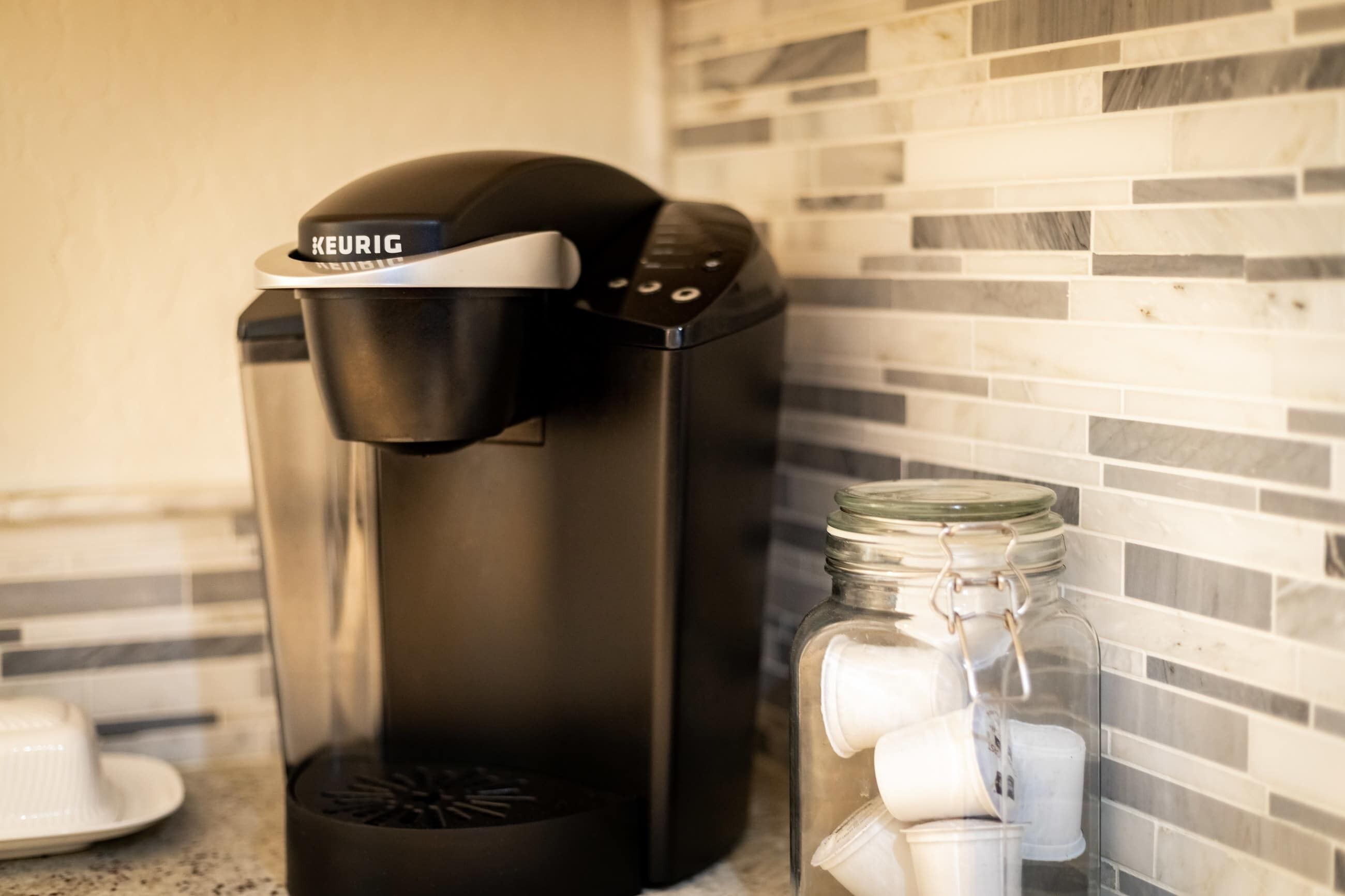 A Keurig coffee maker on a kitchen counter with a tiled backsplash.