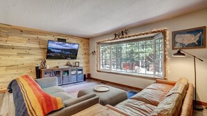 Una sala de estar acogedora con un ventanal grande, un televisor y un mapa de los Estados Unidos en la pared.