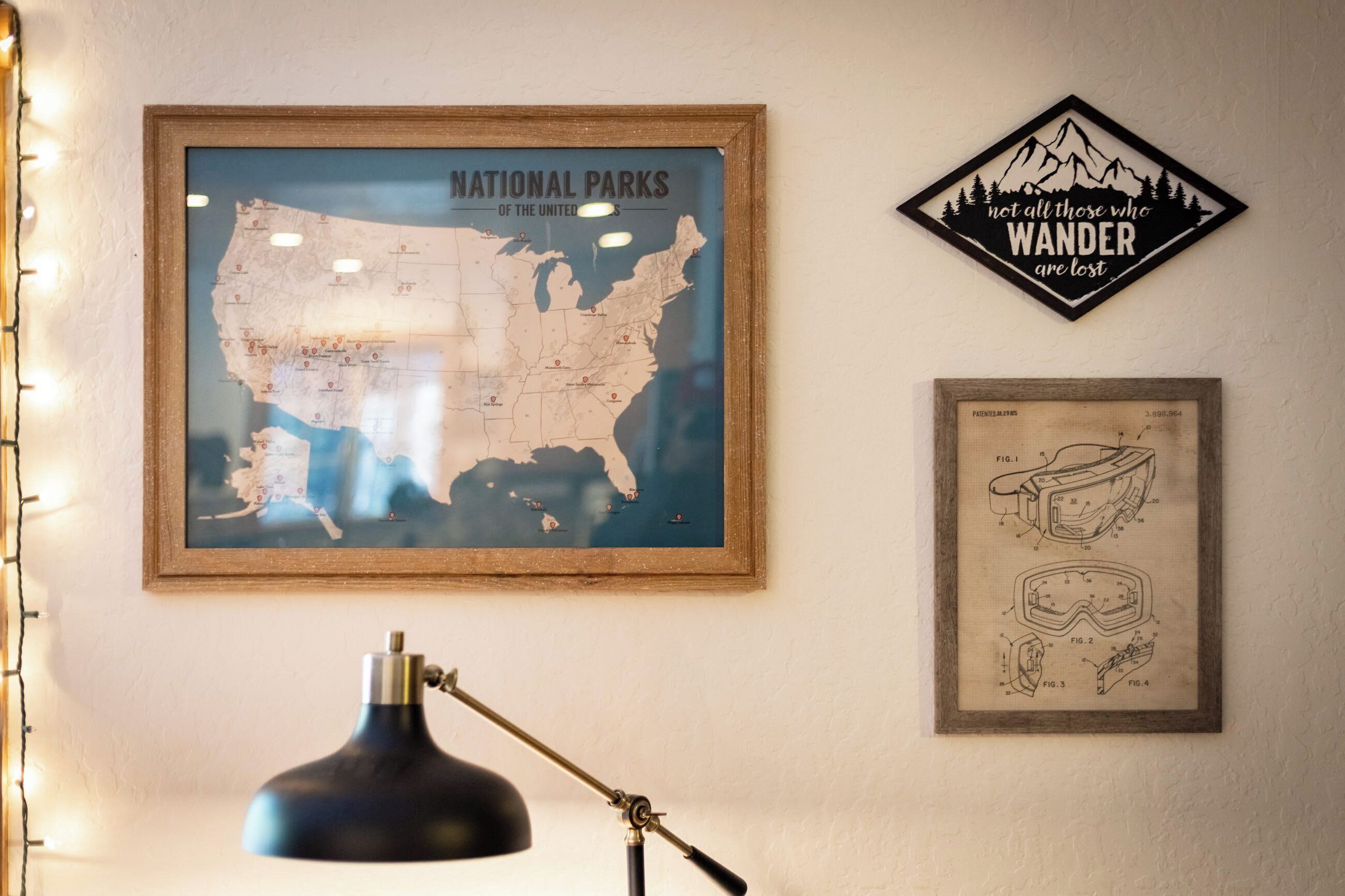 Et indrammet kort over USA med nationalparker markeret, en indrammet patenttegning og en plakat med et motiverende citat.