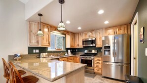 A modern kitchen with wooden cabinets, stainless steel appliances, and a granite countertop.