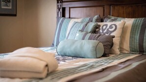 A neatly made bed with striped bedding and multiple pillows, including a decorative one with a number.