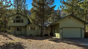 A two-story house with a garage, surrounded by trees.