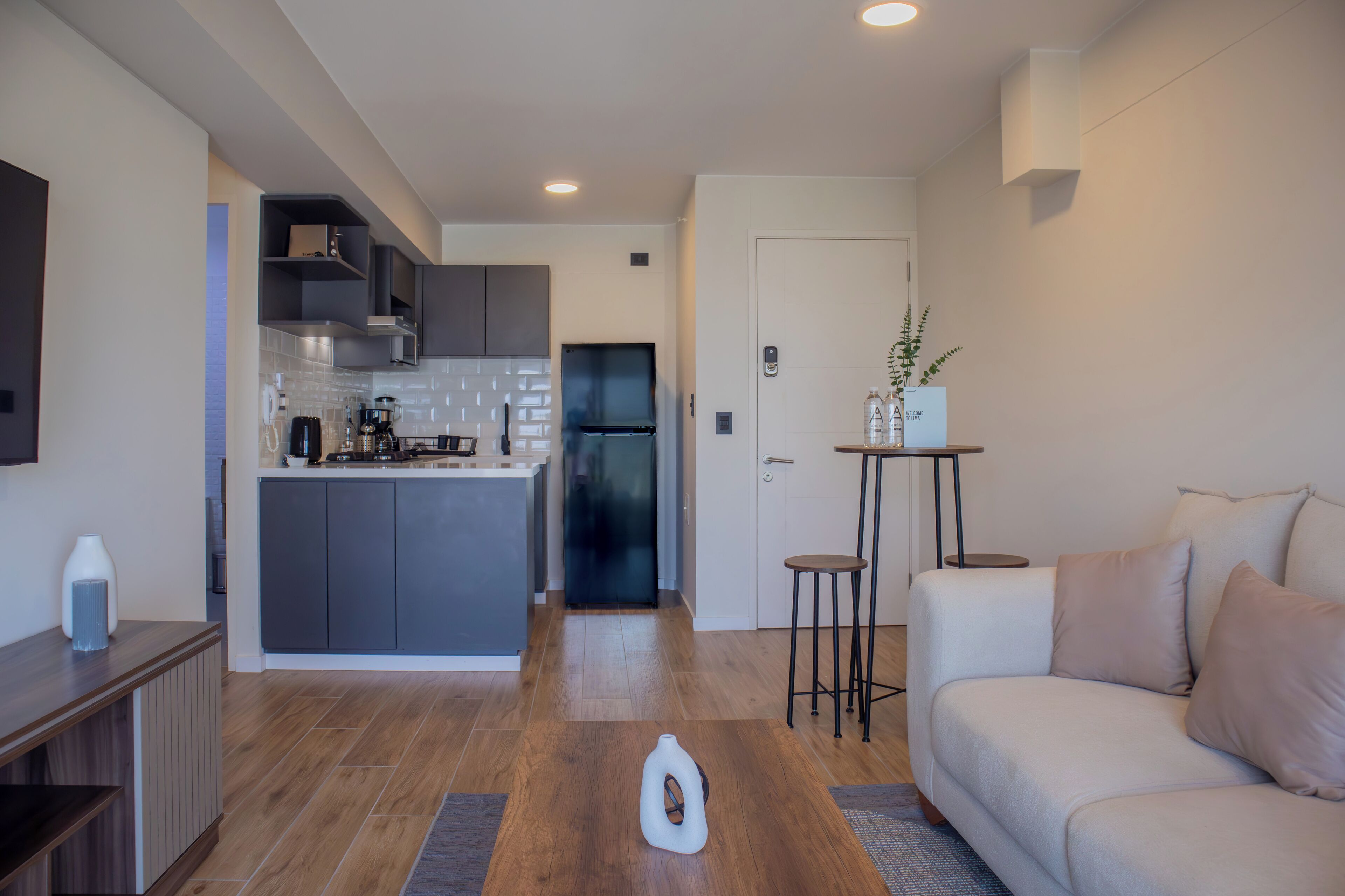 A modern kitchen with grey cabinets, a central island, and a black refrigerator.