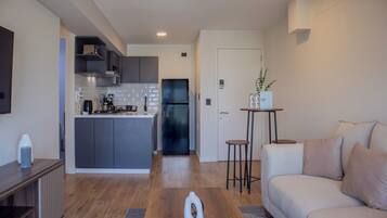A modern kitchen with grey cabinets, a central island, and a black refrigerator.