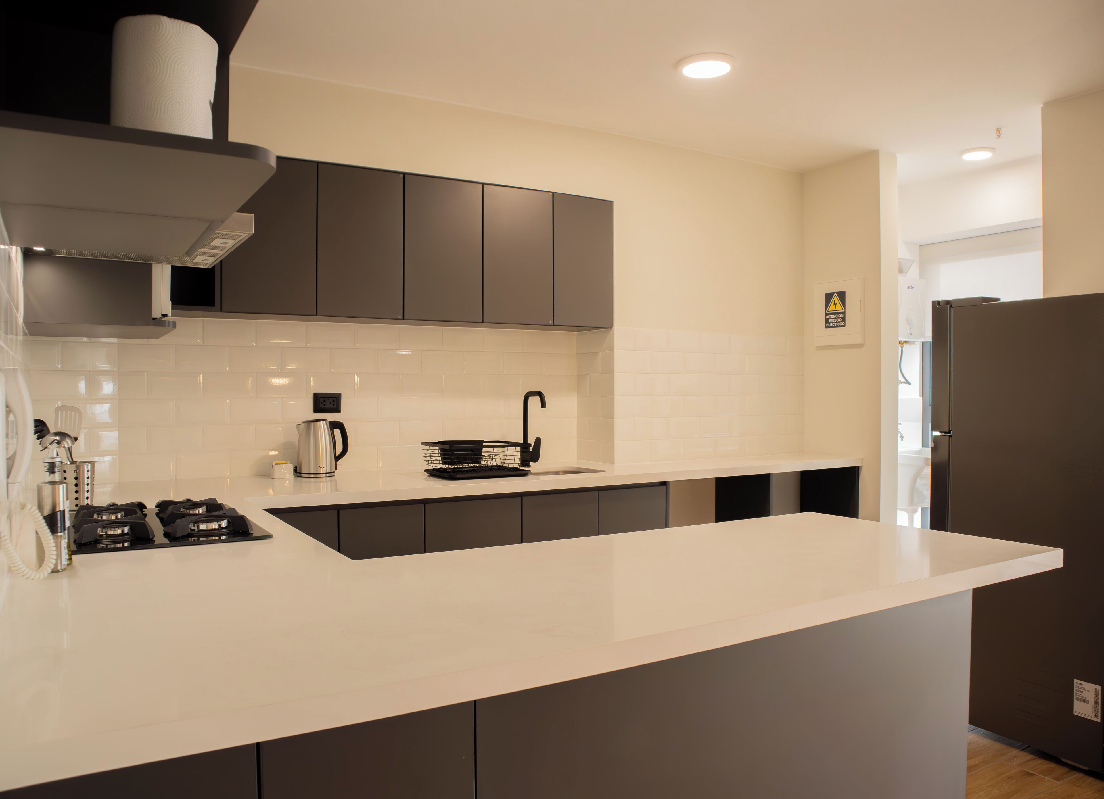 A modern kitchen with a white countertop, dark cabinets, and a stainless steel range hood.
