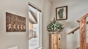 A hallway with a wooden cabinet, a small Christmas tree, a welcome sign, and a map on the wall.