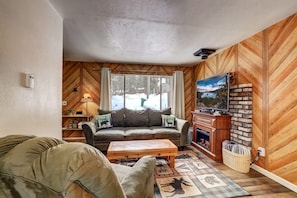 Relax in a cozy living room with a comfortable sofa, flat-screen TV, and brick wall decor.