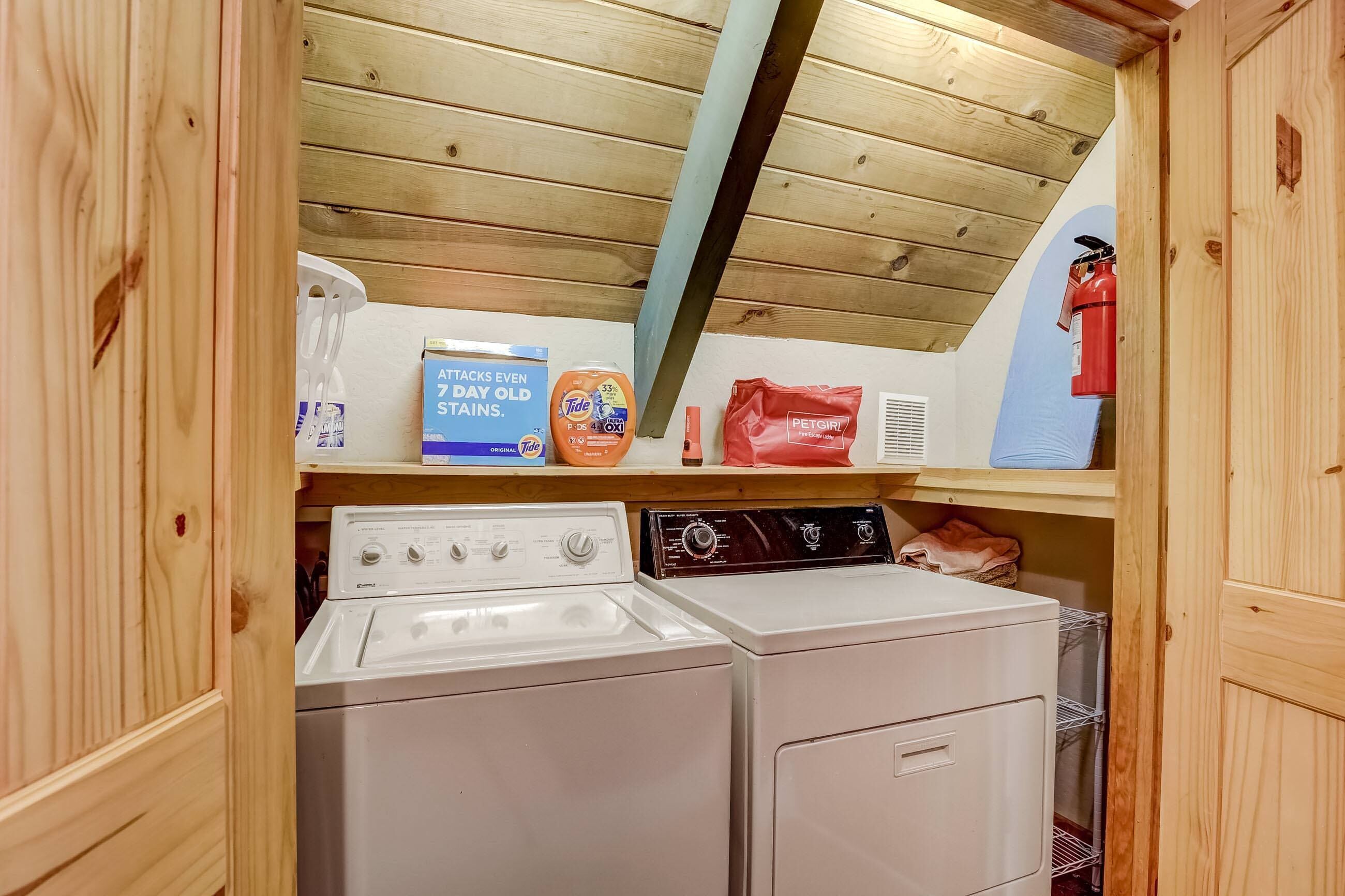 A laundry area with two washing machines, a shelf with cleaning supplies, and a fire extinguisher.