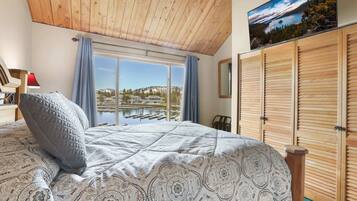 A bedroom with a large bed, a view of a marina, and wooden shutters.