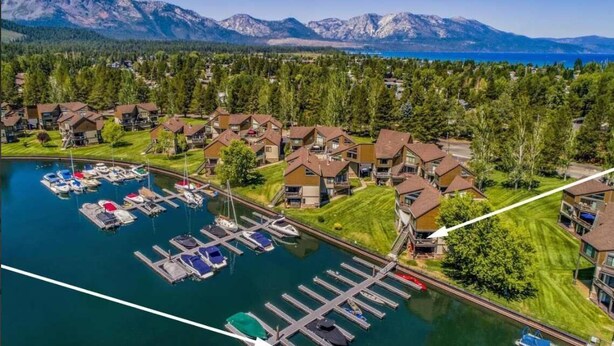 A marina with boats docked, surrounded by residential buildings with a mountainous backdrop. - Tahoe Keys Marina View: Tahoe Keys short term rental (South Lake Tahoe)