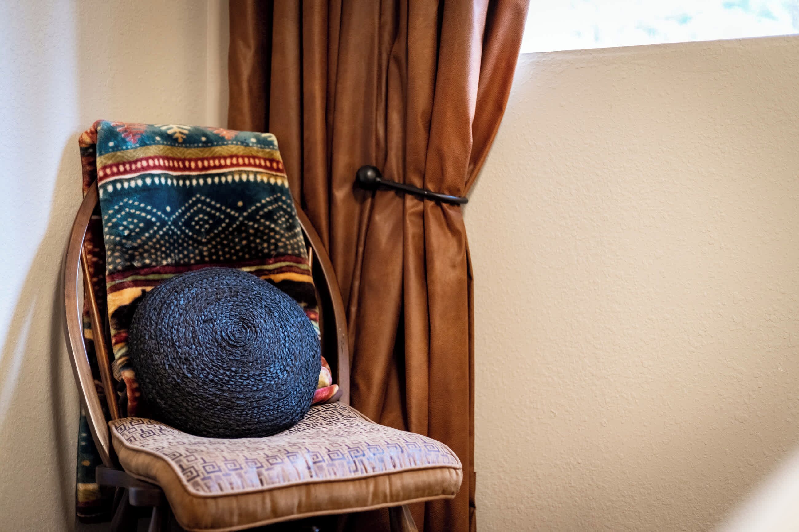 Una silla con un cojín estampado y un sombrero tejido.