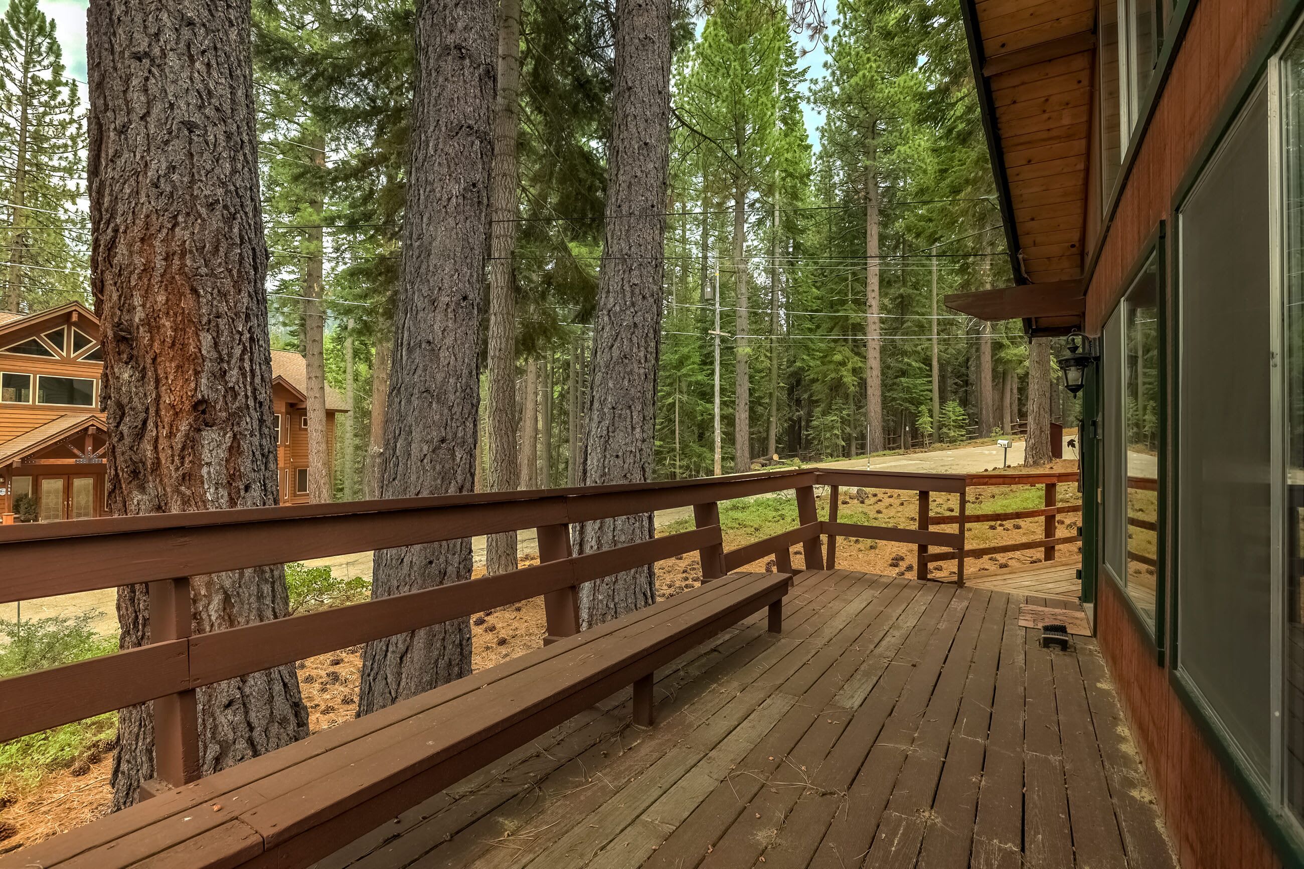 A wooden deck with benches, surrounded by tall trees, overlooking a forested area.