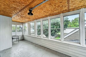 A room with large windows, a wooden ceiling, and a concrete floor.