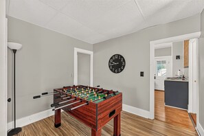 A room with a foosball table, a wall clock, and a door leading to another room.
