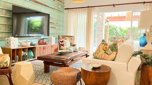 A cozy living room with a TV, wooden shelves, a sofa, and a dining area. - Luxury 2-Bedroom Apartment with Private Mini Pool & Backyard in Las Terrenas (El Limón)