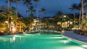 A swimming pool with a wooden bridge, surrounded by palm trees and hotel buildings. - Luxury 2-Bedroom Apartment with Private Mini Pool & Backyard in Las Terrenas (El Limón)