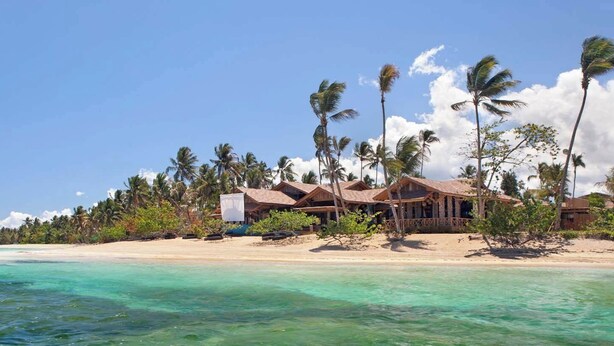 A beachfront resort with wooden buildings, palm trees, and clear turquoise waters. - Luxury 2-Bedroom Apartment with Private Mini Pool & Backyard in Las Terrenas (El Limón)