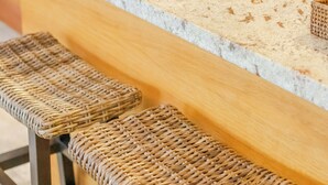 Een keuken met een houten aanrecht en twee rieten barstoelen.