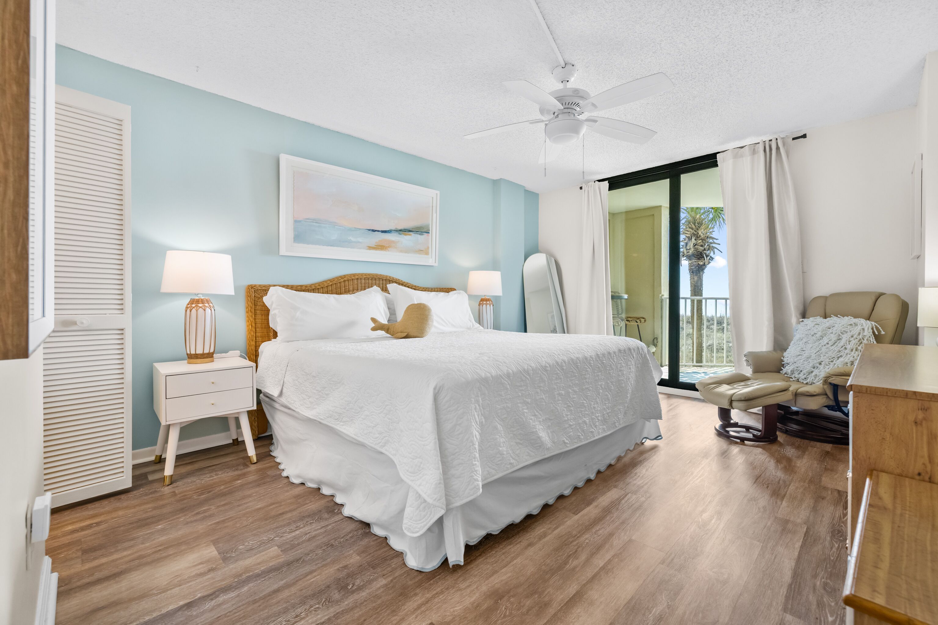 Une chambre à coucher avec un lit, des tables de chevet, une chaise et une vue sur l’extérieur.