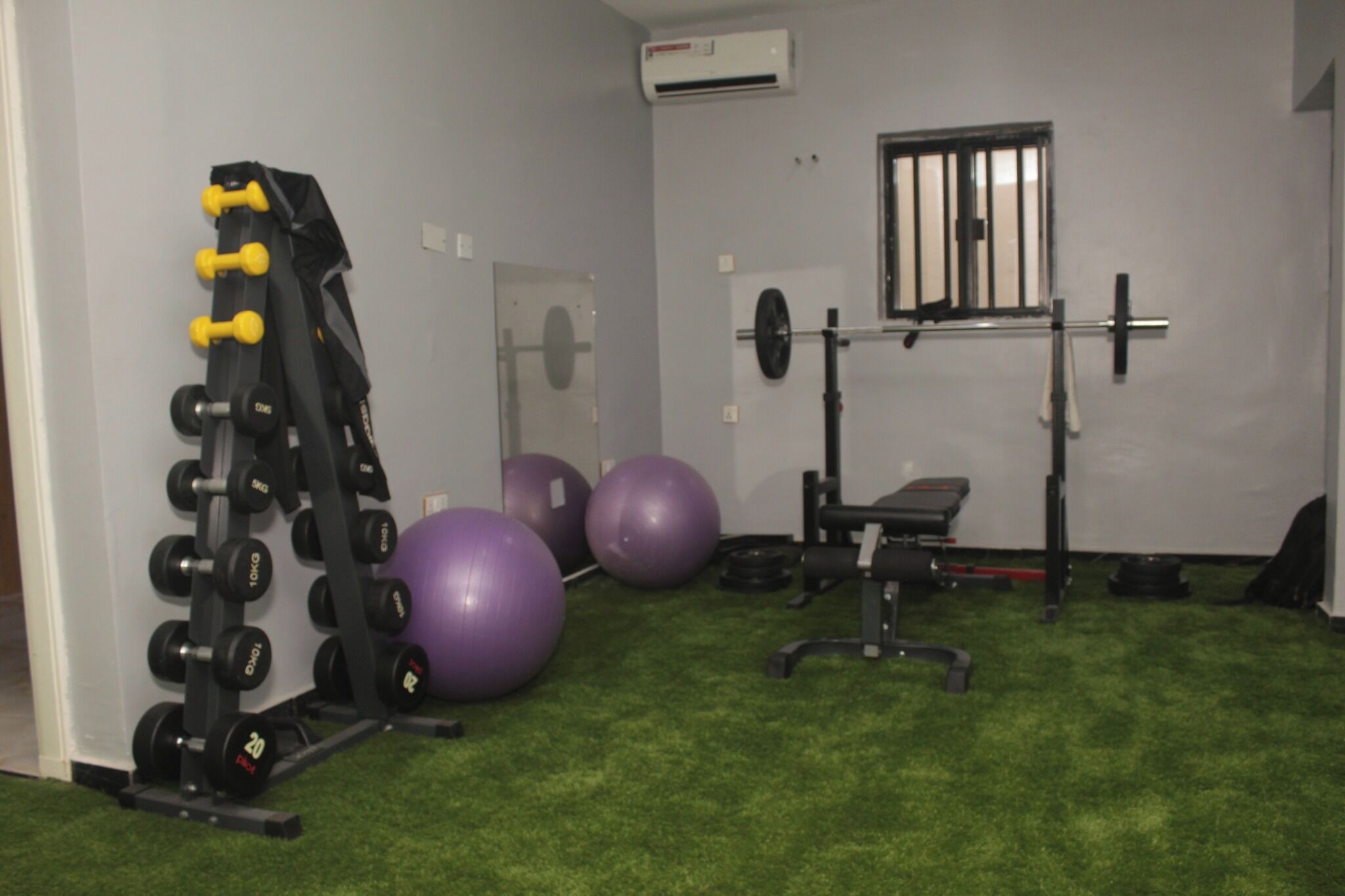 Een sportschool met gewichthefapparatuur, trainingsballen en een bank.