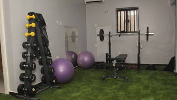 Une salle de sport équipée de matériel de musculation, de ballons d’exercice et d’un banc.